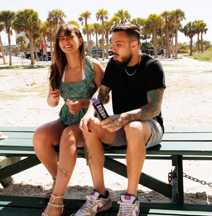 Two friends laughing together on a picnic bench at the beach in Clearwater, Florida