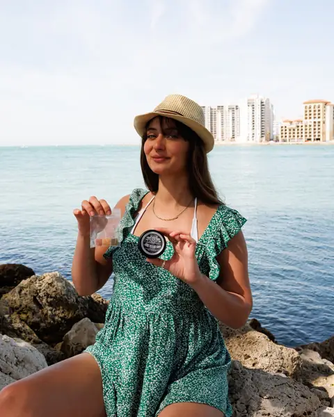A woman in a sun hat on the rocks with the Clearwater, Florida skyline behind her